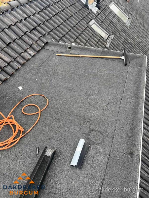 Plat dak reparatie met gereedschap en loodstroken in Burgum