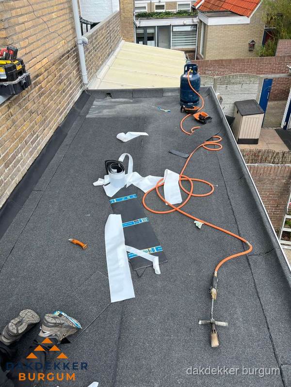 Dakdekkers bezig met bitumen dakbedekking in Burgum