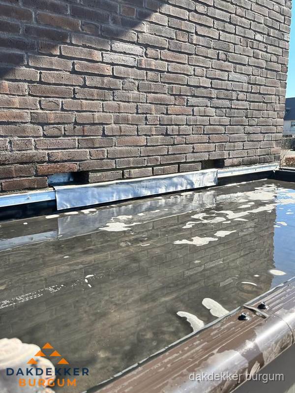 Stilstaand water op plat dak door slechte afwatering in Burgum