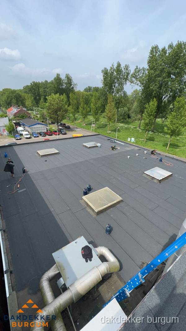 Dakdekker aan het werk op groot plat dak met bitumen in Burgum