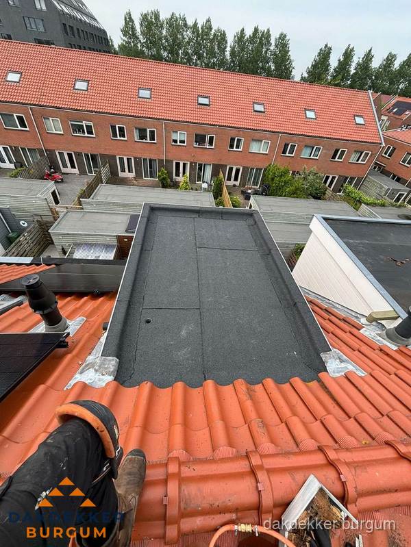 Bitumen dak reparatie op plat dak tussen dakpannen in Burgum